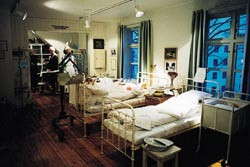 Sygesal 1 med to jernsenger, barnekrok med barneseng og kuv&oslash;se samt stellebord og barnet&oslash;y