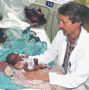 Forfatteren unders&oslash;ker et lite, for tidlig f&oslash;dt barn p&aring; mammaens sykeseng. Kuv&oslash;sen i bakgrunnen. Foto Kristin B&oslash;hler