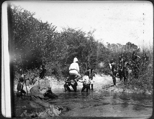 Ekspedisjonen krysser en elv p&aring; veien mellom Kasongo og Lusambo. Bildet er trolig fra den 12. trypanosomiasis-ekspedisjonen&hellip;